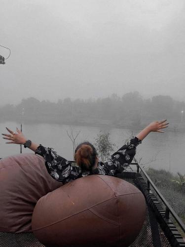a woman sitting on a bean bag by a lake at River Hill Khaokho in Khao Kho