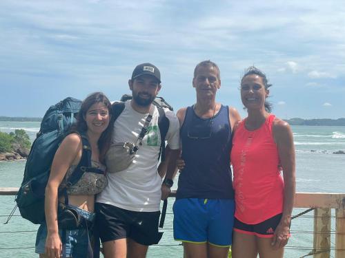 a group of people standing next to the ocean at Kenno's Korner in Weligama