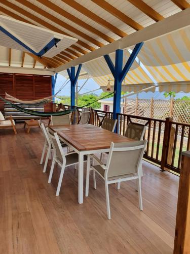 a wooden table and chairs on a deck with a hammock at Chambre créole et sa salle de bain chez Michelle in La Désirade