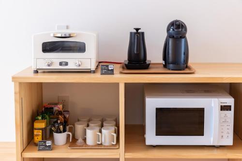 a microwave and a coffee maker on a table at Rinrei terrace 一棟貸切 シングルルーム6部屋 各部屋トイレ シャワー付 in Azumino