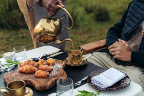 a table with a tea pot and food on it at Pearl Mara in Masai Mara