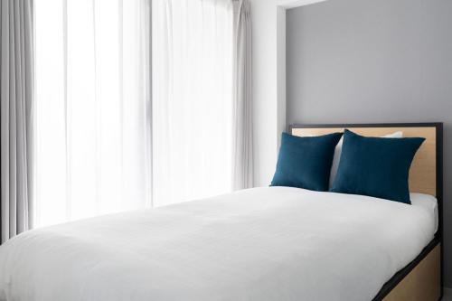 een bed met blauwe kussens voor een raam bij Shinsen Hombe BLD in Tokyo
