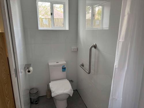 a white bathroom with a toilet and a window at Hearty Center Motel in Katoomba