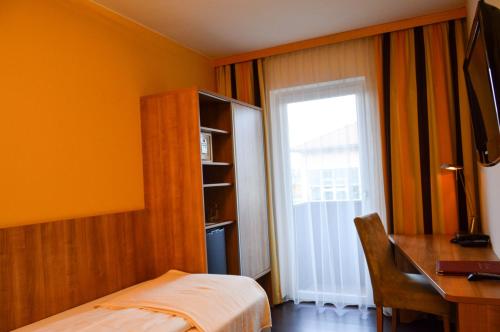 a bedroom with a bed and a desk and a window at Hotel Römerhof in Tulln