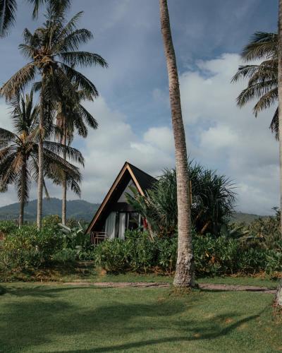 a house with palm trees in front of it at Desa Cabins in Balian