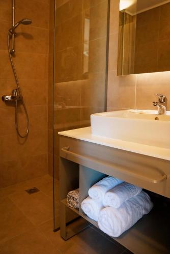 a bathroom with a sink and a shower and towels at Acharavi Beach Hotel in Acharavi
