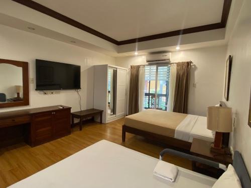 a hotel room with a bed and a television at Club Balai Isabel Recto 102 Lakeshore Room in Talisay