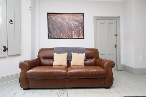 a brown leather couch sitting in a living room at Central Cardiff Victorian Town House Free parking in Cardiff