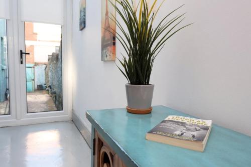 a book sitting on a table with a potted plant at Central Cardiff Victorian Town House Free parking in Cardiff