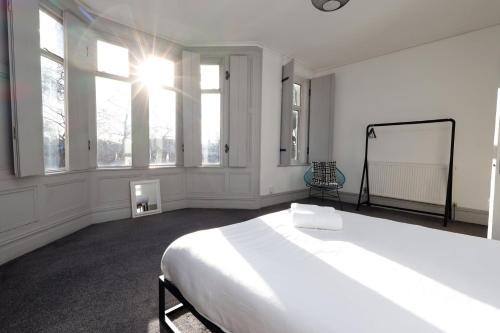 a white bedroom with a large bed and windows at Central Cardiff Victorian Town House Free parking in Cardiff