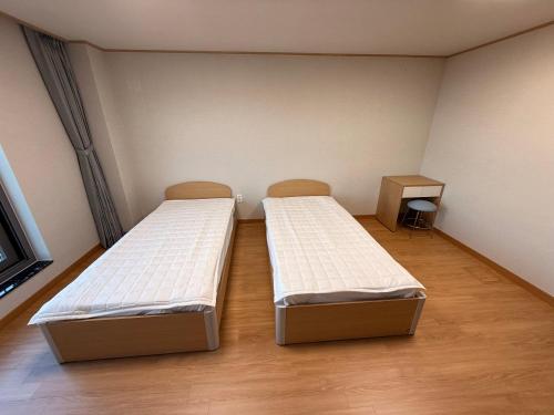 two beds in an empty room with at DMZ Hotel & Tour Guide in Paju