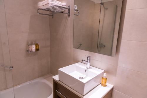uma casa de banho com um lavatório, um espelho e uma banheira em Dazzler by Wyndham Polo em Buenos Aires