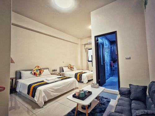 a hotel room with two beds and a couch at Peninsula Travel B&B in Hengchun