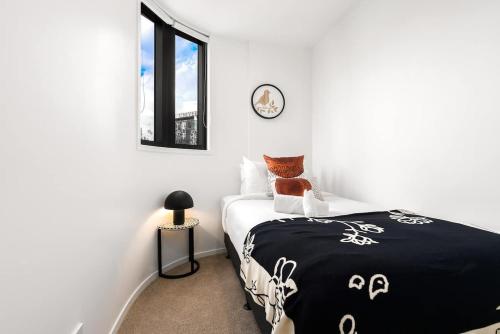 a bedroom with a bed with a black and white blanket at Luxury Design Parkside Living in CBD vs Aircon in Auckland