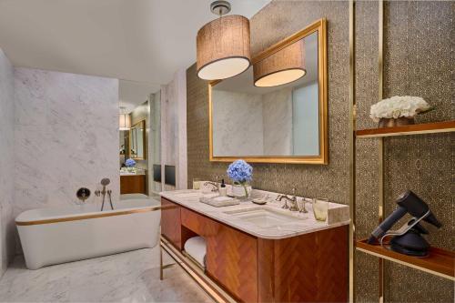 a bathroom with a tub and a sink and a tub and a mirror at Rosewood Bangkok in Bangkok