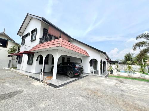 a car parked in front of a white house at Teratai Homestay Batu Buruk in Kuala Terengganu