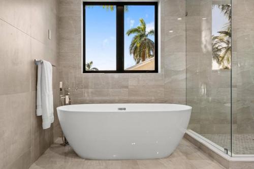 a white bath tub in a bathroom with a window at Heated Pool & Rooftop Near Intracoastal in Boynton Beach