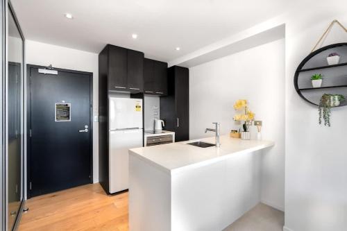 a kitchen with a white counter and a black refrigerator at The Heart of City Living with Incredible City & Skytower View Nearby Queen St in Auckland