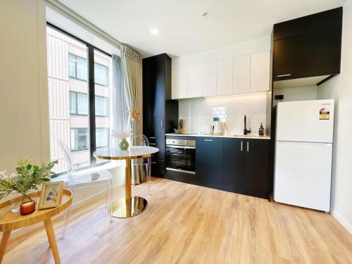 a kitchen with a white refrigerator and a table at Stylish Cozy Studio Nearby SkyTower-Pool Gym Sauna in Auckland