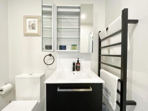 a white bathroom with a sink and a toilet at Stylish Cozy Studio Nearby SkyTower-Pool Gym Sauna in Auckland