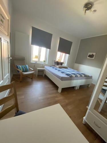 a bedroom with a bed and a chair and windows at Pension Grunwald in Sehnde