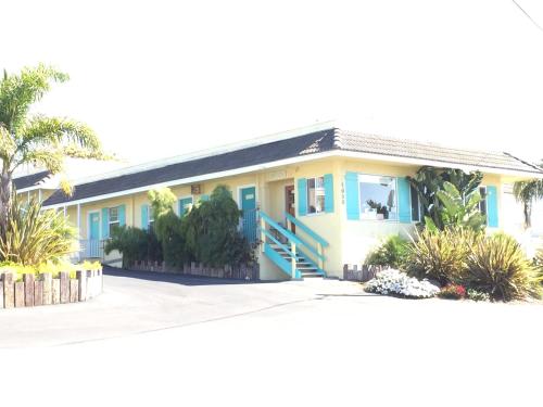 a house with blue doors and palm trees at Beach Bungalow Inn and Suites in Morro Bay