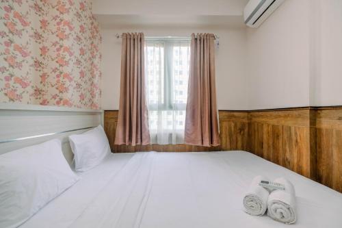 a bedroom with a bed with two towels on it at Minimalist and Comfy 2BR at Titanium Square Apartment By Travelio in Jakarta