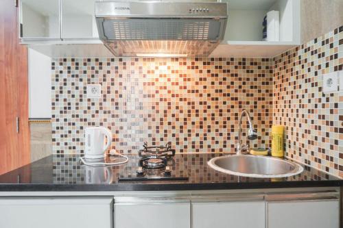 a kitchen with a sink and a counter top at Minimalist and Comfy 2BR at Titanium Square Apartment By Travelio in Jakarta