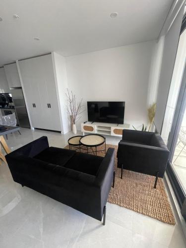a living room with two black couches and a tv at 1 Bedroom Apartment with balcony in Sydney