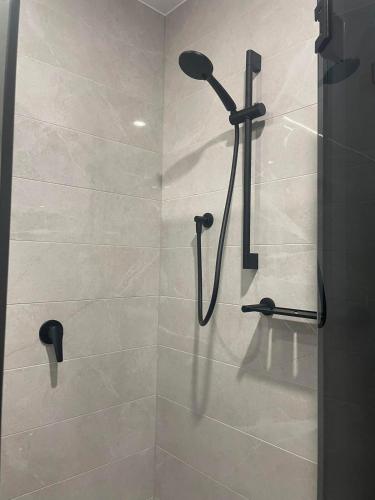 a shower with a shower head in a bathroom at 1 Bedroom Apartment with balcony in Sydney