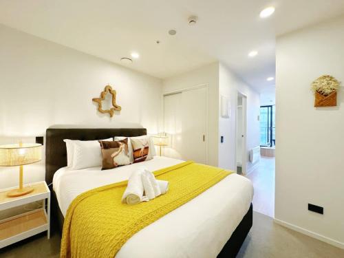 a bedroom with a large bed with a yellow blanket at Lime-Fresh Garden Atmosphere CBD 1B Pool Sauna Gym in Auckland