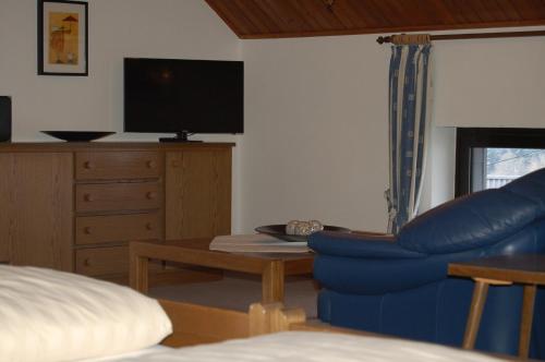 a living room with a blue chair and a tv at Landgasthaus Pfahl in Wershofen