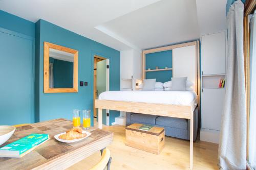 - une chambre avec un lit aux murs bleus et une table dans l'établissement Contemporary studio in the heart of Morzine, à Morzine