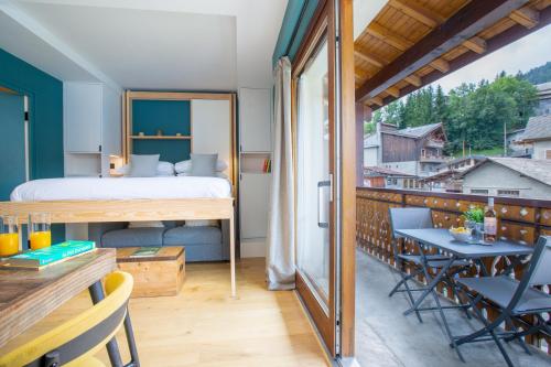Cette chambre dispose d'un lit et d'un balcon avec une table. dans l'établissement Contemporary studio in the heart of Morzine, à Morzine