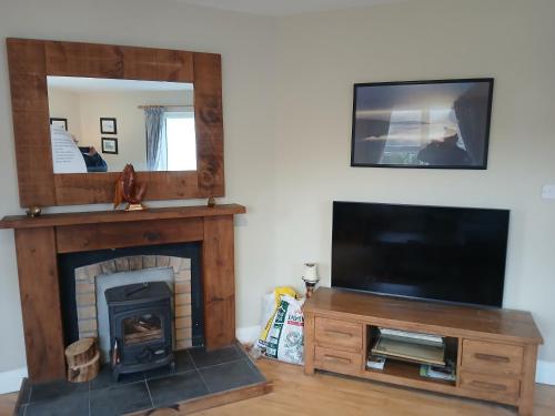 a living room with a fireplace and a flat screen tv at Watersedge in Mulranny