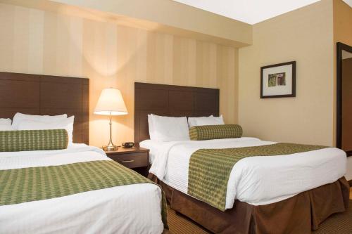 a hotel room with two beds with green and white sheets at Quality Inn and Conference Centre in Pembroke