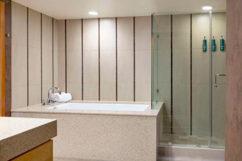 a bathroom with a tub and a glass shower at Hilton Orange County/Costa Mesa in Costa Mesa