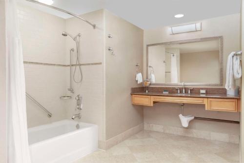 a bathroom with a tub and a sink and a mirror at Hilton Orange County/Costa Mesa in Costa Mesa