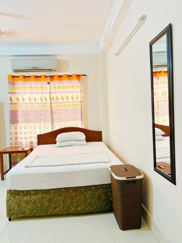 a bedroom with a bed and a mirror and a window at Maya Eco Guest House in Dhaka