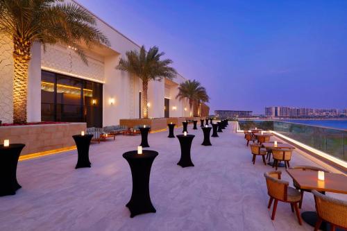 a hotel patio with tables and chairs and candles at Hilton Abu Dhabi Yas Island in Abu Dhabi