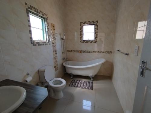 a bathroom with a tub and a toilet and a sink at Shalakwe Hills-Inn Guesthouse Kasane in Kasane