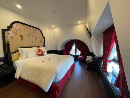 a bedroom with a large white bed with red curtains at The ORCHID PREMIUM Hotel in Hue