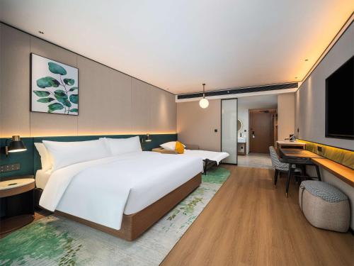 a hotel room with a large bed and a desk at Hilton Garden Inn Hefei High-Tech Zone in Hefei