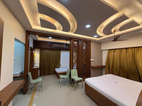 a bedroom with a bed and a table and chairs at Marudhan Grand in Kumbakonam