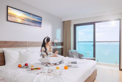 a woman sitting on a bed in a hotel room at PANAMA Nha Trang Hotel in Nha Trang