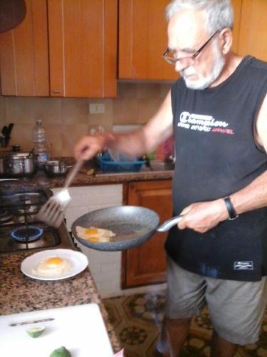 a man in a kitchen preparing food in a wok at La Via Del Mare in Arenella