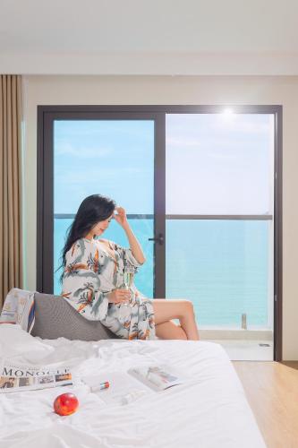a woman sitting on a bed in front of a window at PANAMA Nha Trang Hotel in Nha Trang