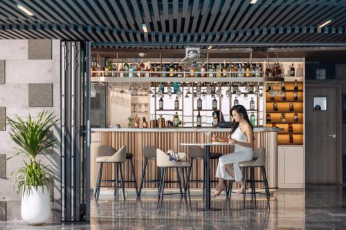 a woman sitting at a bar in a restaurant at PANAMA Nha Trang Hotel in Nha Trang