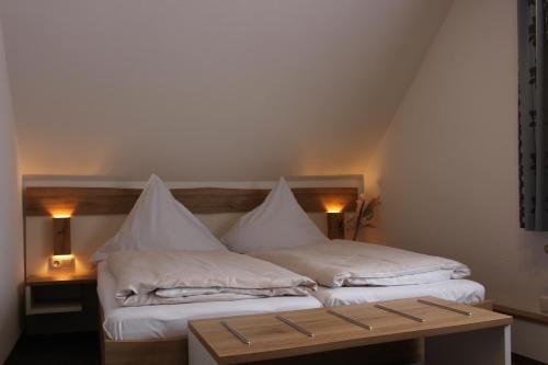 a bed with white sheets and pillows on it at Hotel Berghof Wasserkuppe & Gästehaus Fuldaquelle in Gersfeld