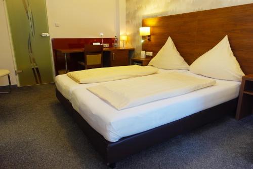 a bedroom with a large bed with a wooden headboard at Hotel Berghof Wasserkuppe & Gästehaus Fuldaquelle in Gersfeld